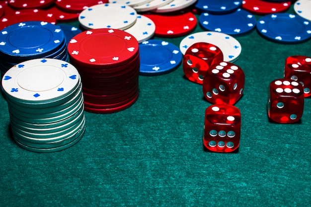 Stack of casino chips and red dices on green poker table