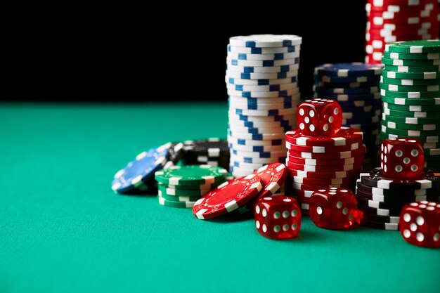 Stack of casino gambling chips and dices on green table