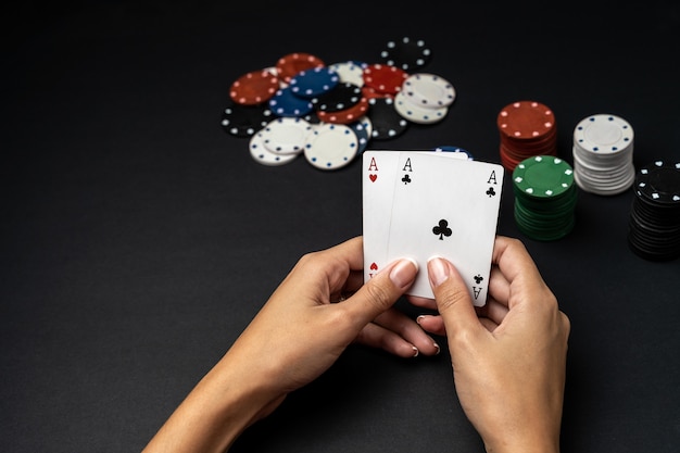 テーブルの上の2つのエースでチップと女性の手のスタック。ポーカーゲームのコンセプト