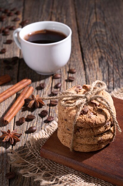 Stack of chocolate chip cookies an cup of coffee on old wooden table