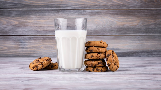 A stack of chocolate chip cookies lies near a glass of milk. Calcium-rich milk.