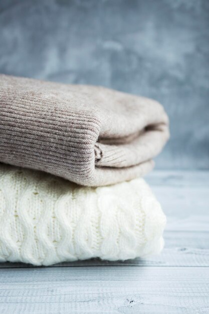 Stack of clean freshly laundered, neatly folded women's clothes on wooden table. Pile of  sweaters