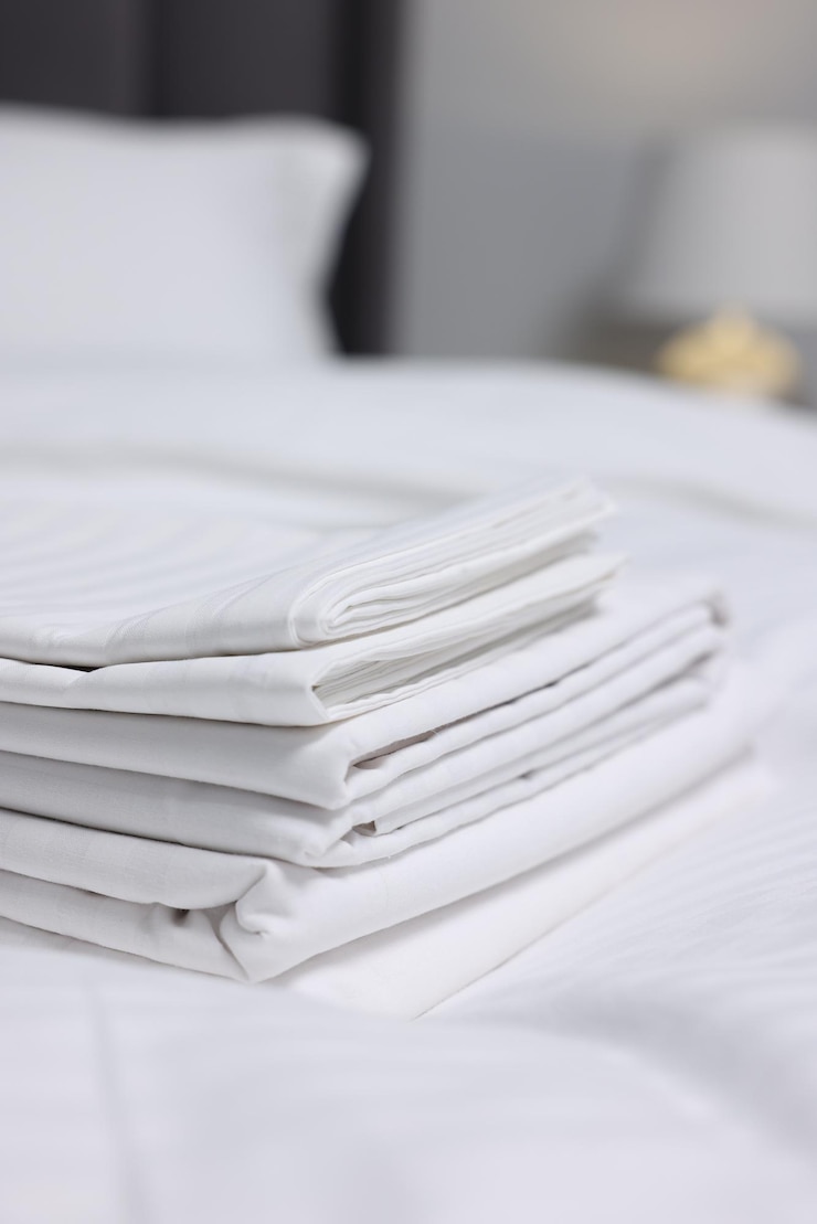 Photo stack of clean linens on bed indoors closeup