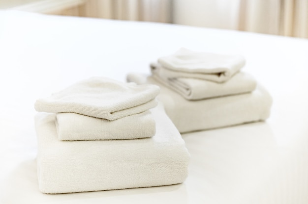 호텔 침대에 깨끗한 수건 더미.