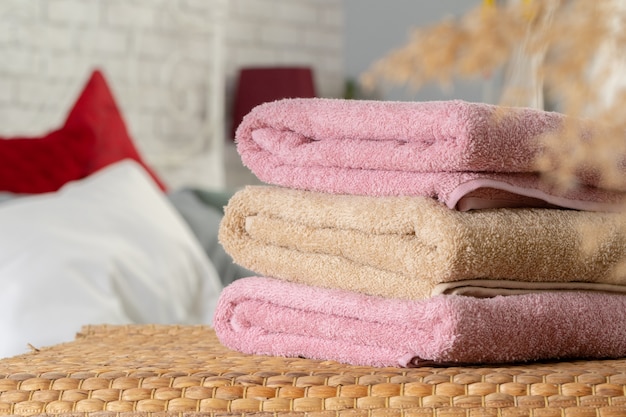 Stack of clean towels on wooden table in bedroom