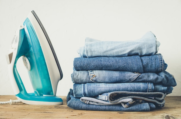 Stack of clothes and electric iron on the table