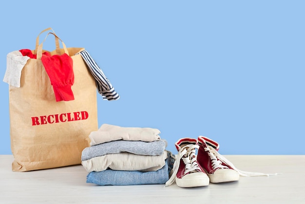 a stack of clothes shoes and a paper bag with an inscription on a blue background