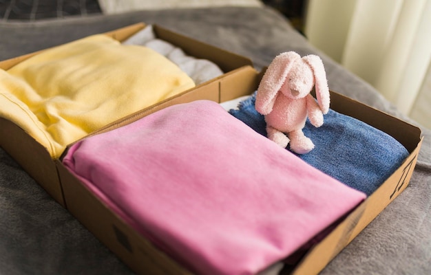 Фото Сложите одежду для сортировки и пожертвования в картонные коробки с игрушечным кроликом для детей.