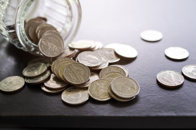 Stack coin 5 baht with jar on black wooden table