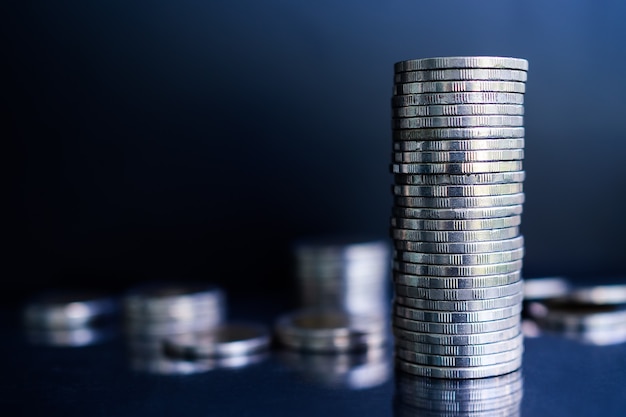 Stack coin on dark black and blue table.