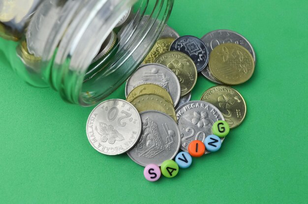 Stack of coins and alphabet bead with text SAVING Financial concept