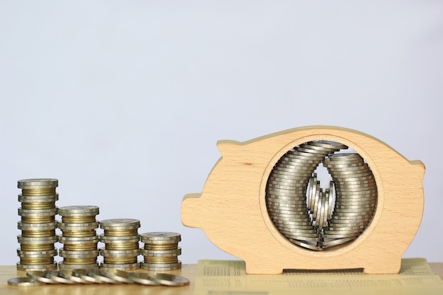 Stack of coins money in piggy bank wood on white background, Saving money for prepare in future and investment concept