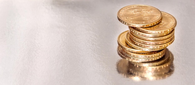 Stack of coins on silver reflective background.