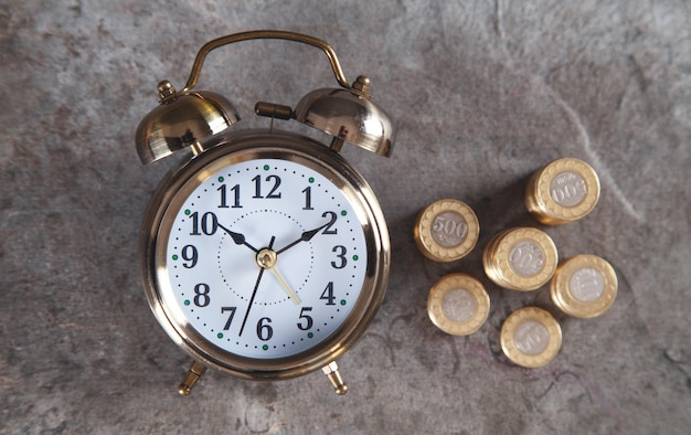 Stack of coins with alarm clock