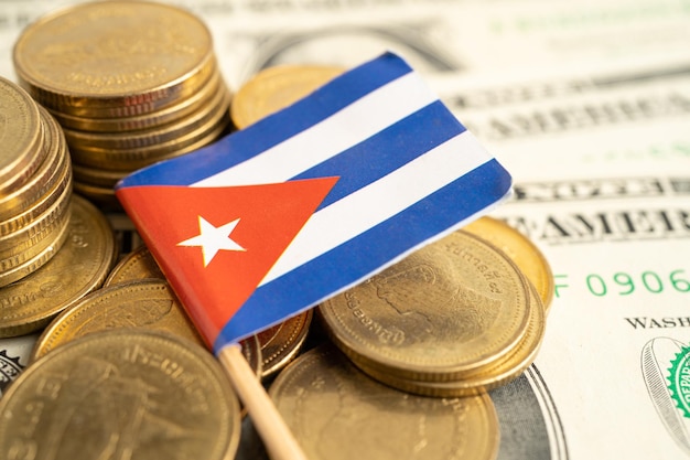 Stack of coins with Cuba flag and US dollar banknotes