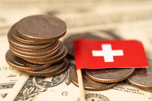 Stack of coins with Switzerland flag on USA banknotes.