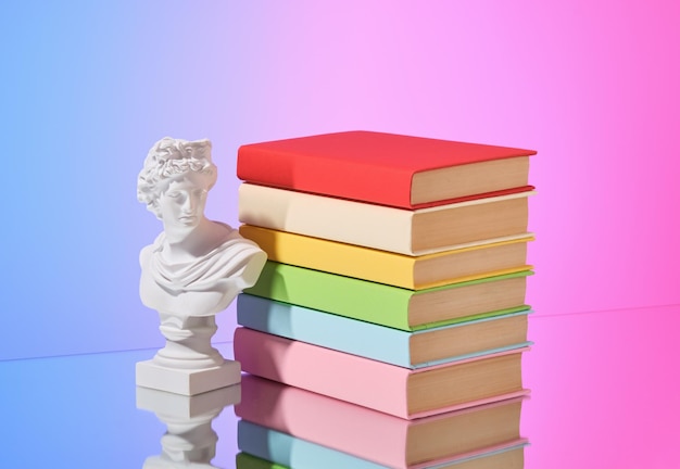 Foto una pila di libri colorati e una statuetta apprendimento e conoscenza