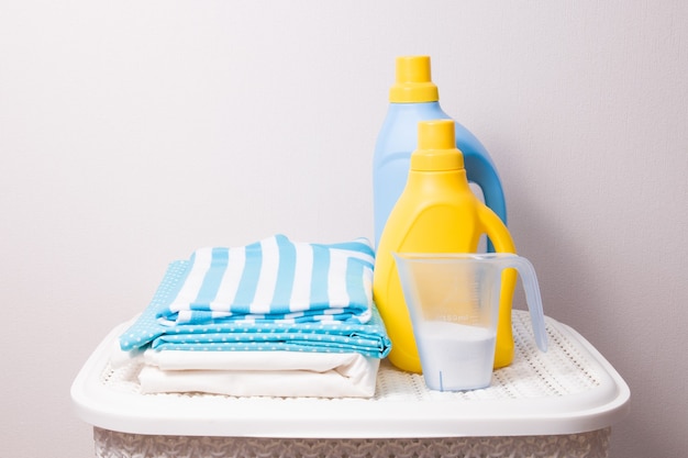 色付きの洗濯物、計量カップの洗剤、黄色とボトルの洗濯用洗剤のスタック