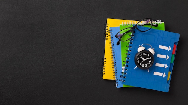 Stack of colored school notebooks and an alarm clock