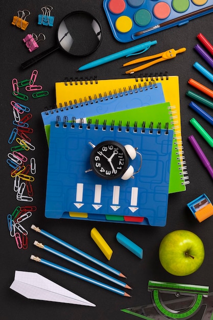 Stack of colored school notebooks and an alarm clock