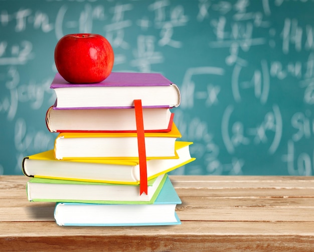 Stack of colorful books and fresh apple