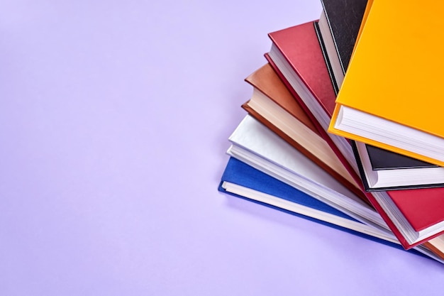 Stack of colorful books on purple background