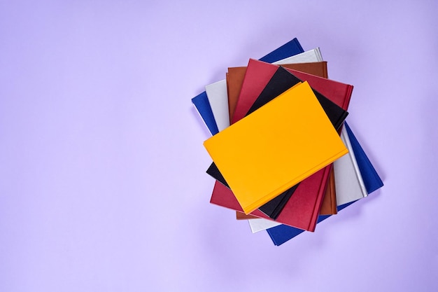 Stack of colorful books on purple background