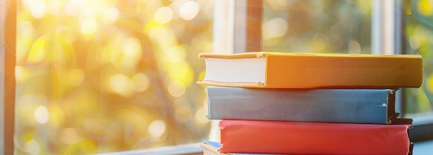 A stack of colorful books on top of each other on the floor with blurred glass window background