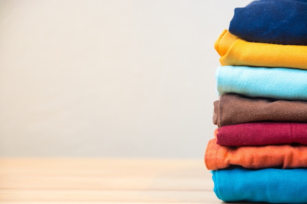 Stack of colorful clothes on wood table, Housework and objects concept