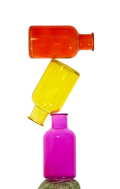 Foto una pila di bottiglie di vetro colorate su una roccia sullo sfondo bianco