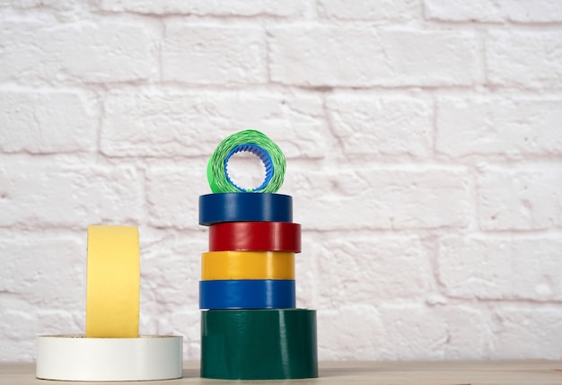 Stack of colorful insulating tape on white brick wall background