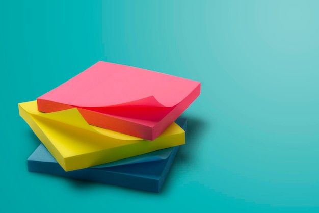 A stack of colorful office sticky notes on a turquoise background Place for text Mocap