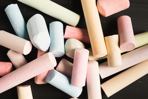 Stack of colorful pastel pieces of chalk over blackboard