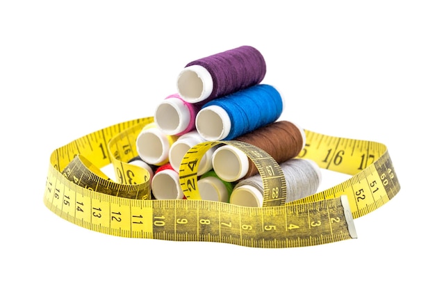 Stack of colorful sewing threads with measuring tape on white background