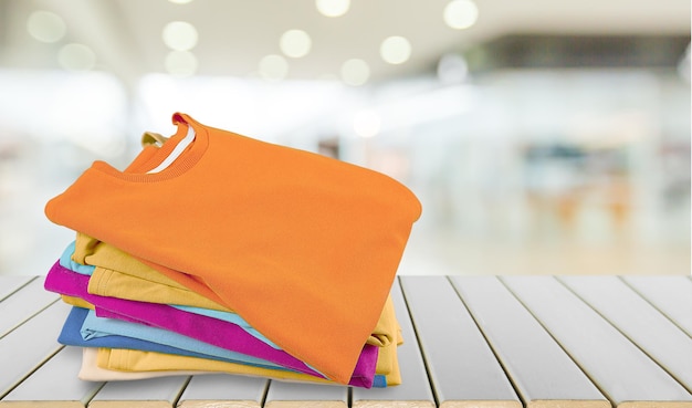 Stack of colorful t-shirts on wooden table