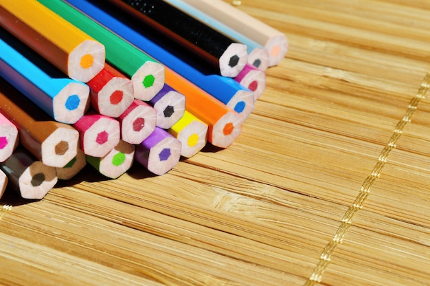 Stack colour pencils on wooden background.