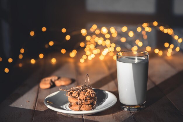 木製の背景コンセプトのクリスマスと休日でサンタのためにクッキーとミルクのグラス