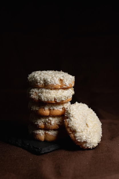 Stack of cookies with coconut flakes placed on slate board on table