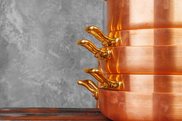 Stack of copper cooking pans on wooden table close up