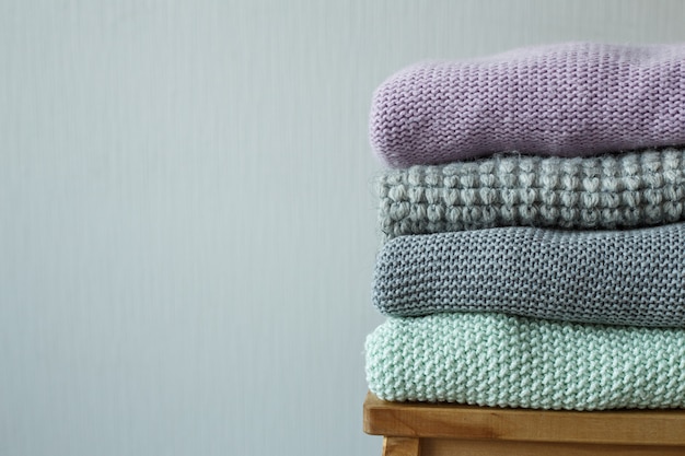 Stack of cozy knitted clothes on a wooden ladder