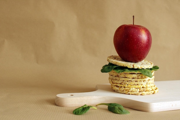 A stack of crispbreads and spinach with a red apple on top