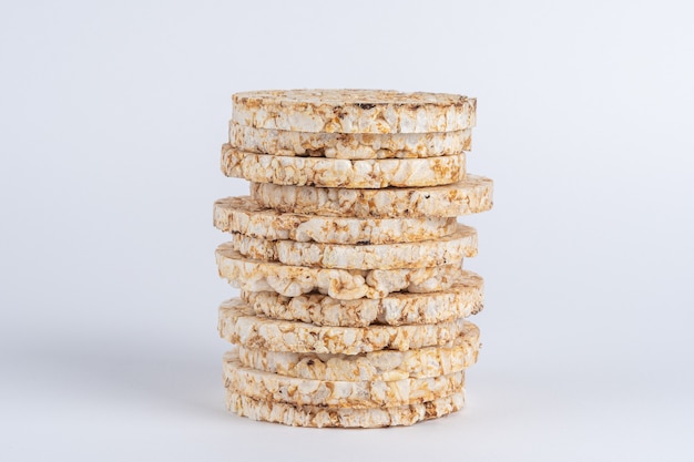 Stack of crunchy rice cakes on white table.