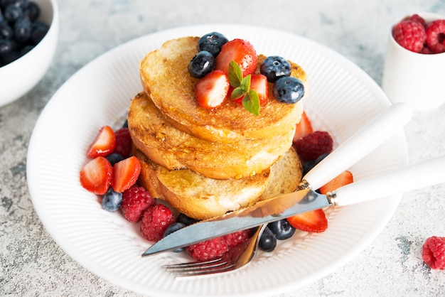 A stack of crunchy toast with honey and berries for Breakfast, close-up