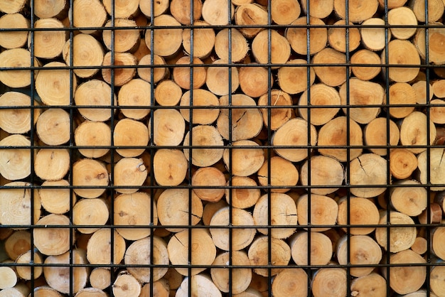 Stack of cut log woods in a metal cage for background or banner