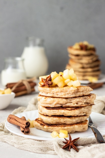 Stack of delicious apple pancakes with fried caramelized apples and spices. 