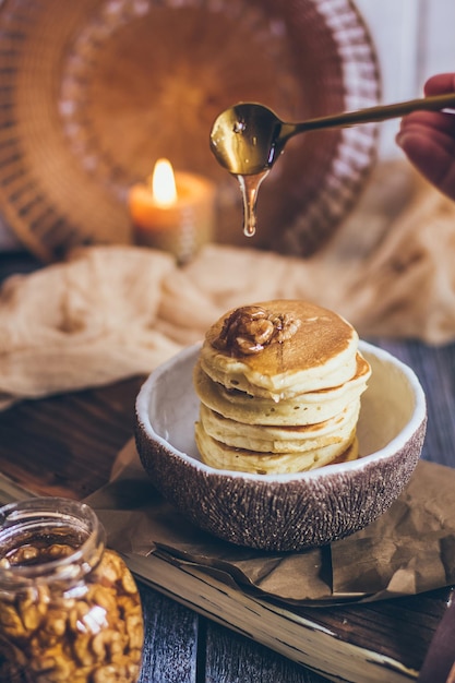 Stack of delicious pancakes with honey, nuts on wooden background
