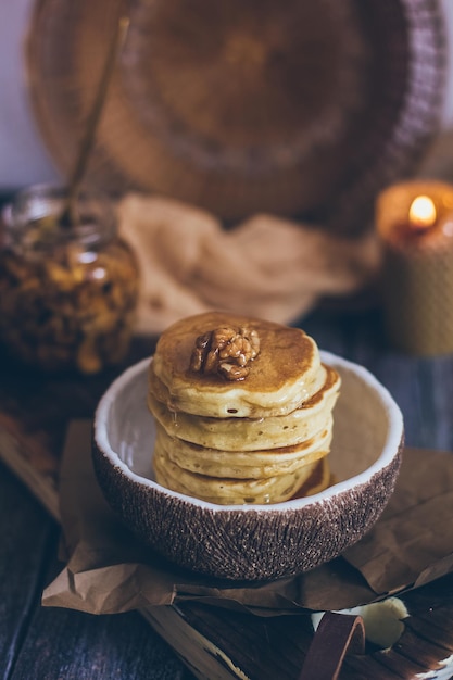 Stack of delicious pancakes with honey nuts on wooden background