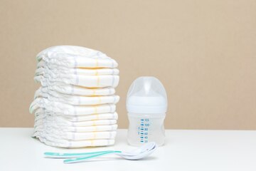 Premium Photo | Stack of diapers with bottle of milk and spoons, baby's ...