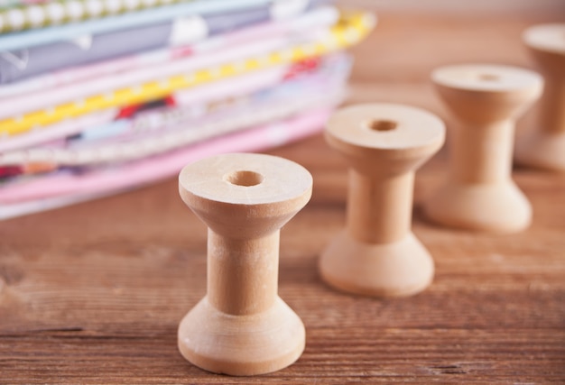 Stack of different colors cloth with empty wooden thread spools 