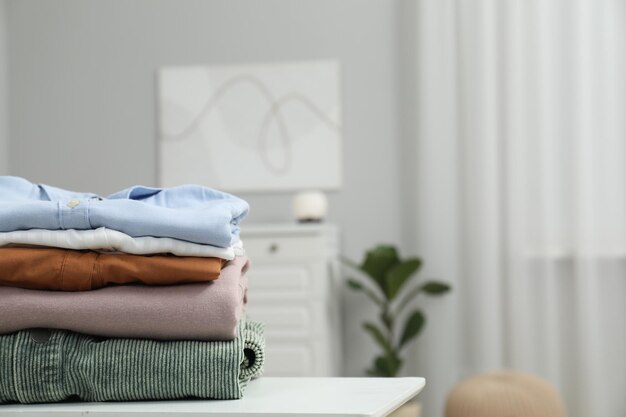 Photo stack of different folded clothes on table indoors closeup space for text